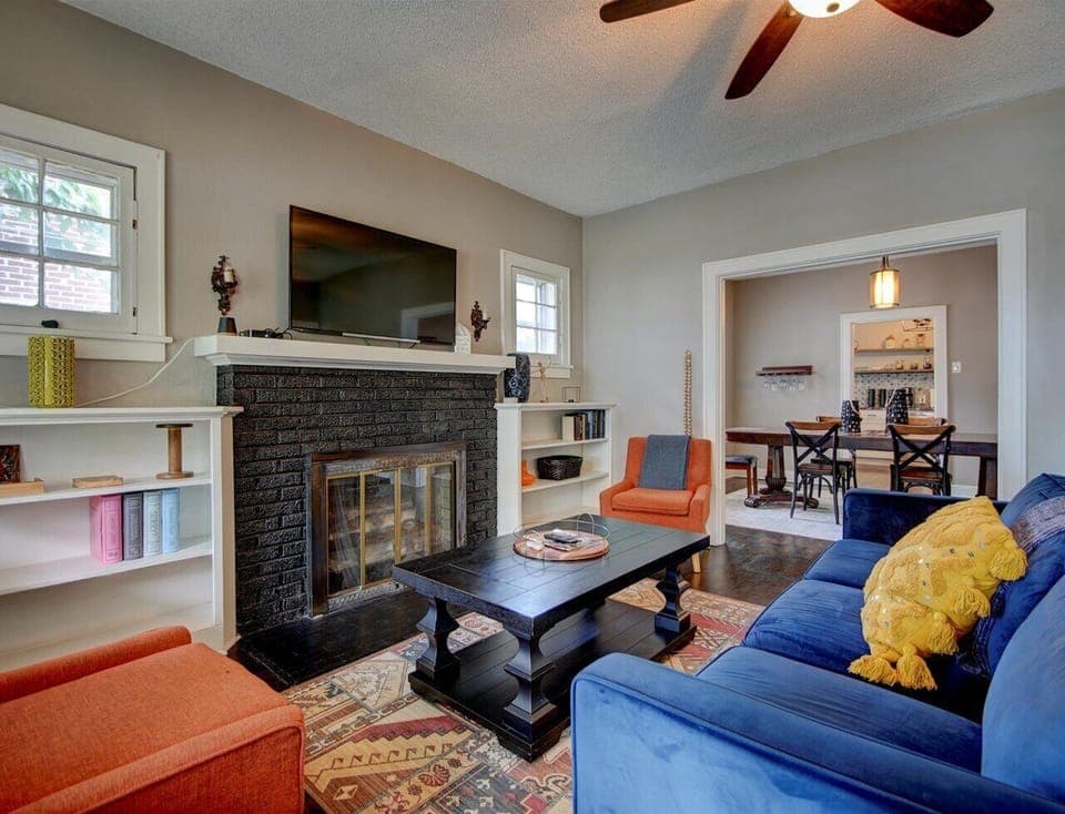 Main living room with fireplace and AppleTV, Kick back on the plush blue sofa and enjoy the cozy space with smart TV and bold modern decor. The perfect welcome to your stay.