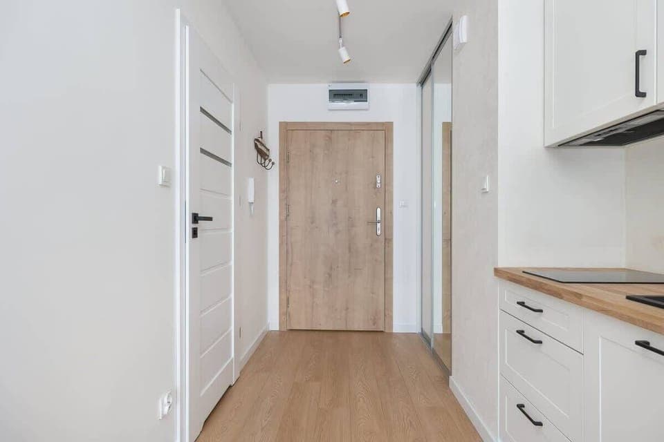 A minimalist hallway with light-colored walls and wooden flooring, giving the space a fresh and elegant feel.