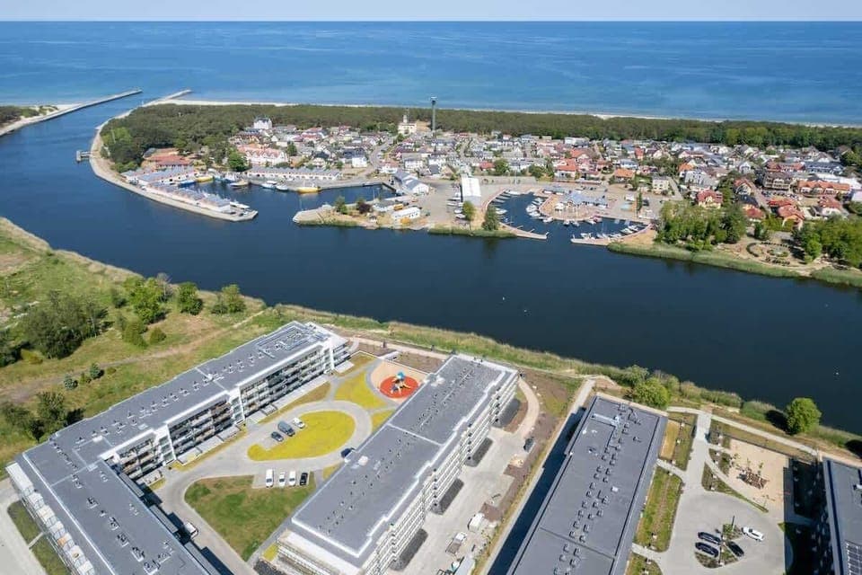 An aerial view of the area with buildings, water, and greenery highlights the apartment’s attractive location.