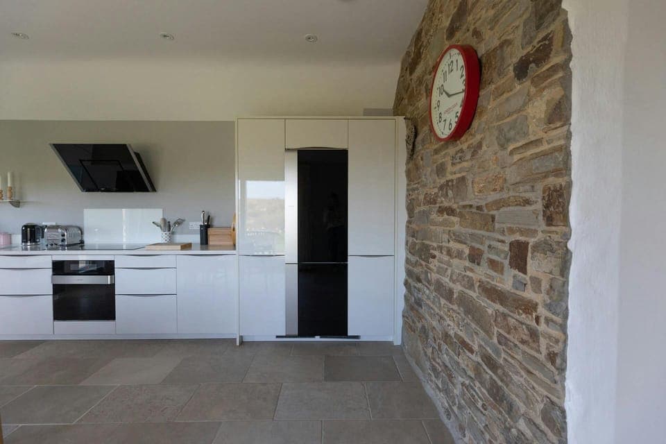 Kitchen with white gloss base cupboards. Electric cooker and extractor hood, fridge, kettle and toaster