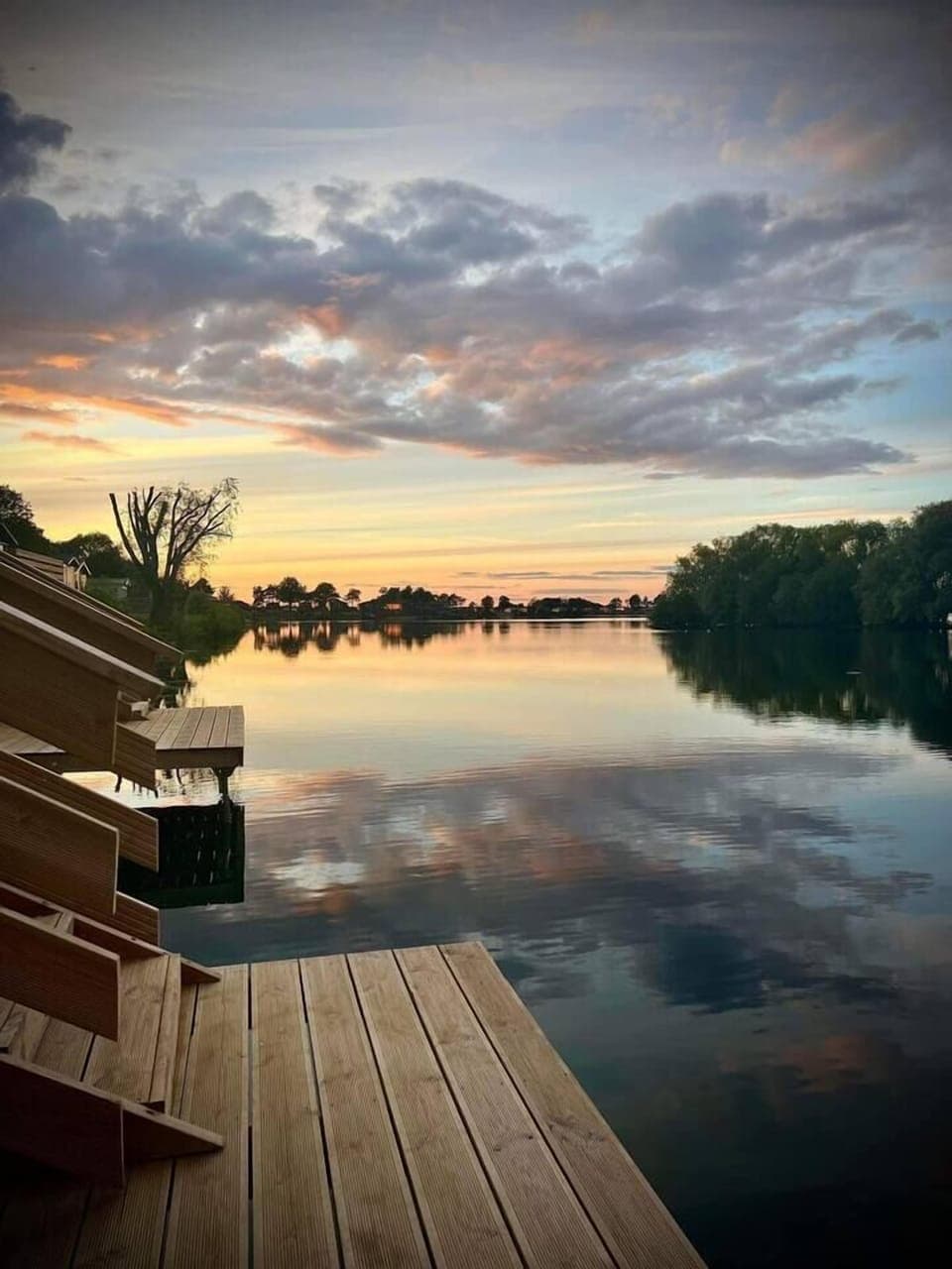 A breathtaking sunrise paints the sky with vibrant hues as it reflects on the calm waters of the lake, creating a magical spectacle from the lower jetty.