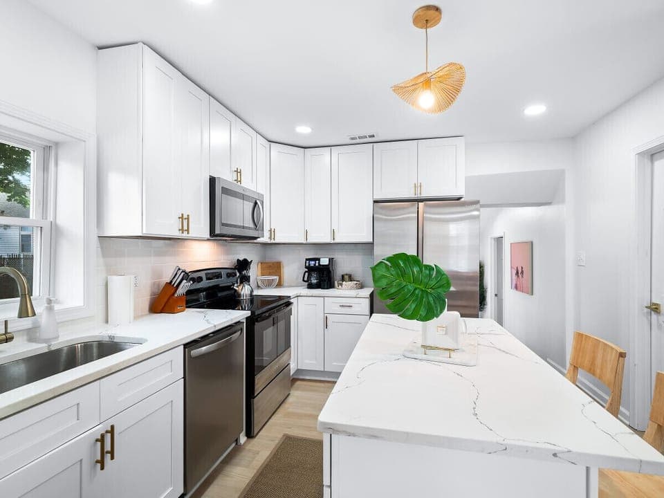 Sleek kitchen with stainless steel appliances and bright white cabinets   - Spacious island with bar seating perfect for group dining   - Fully equipped Airbnb kitchen ideal for extended stays