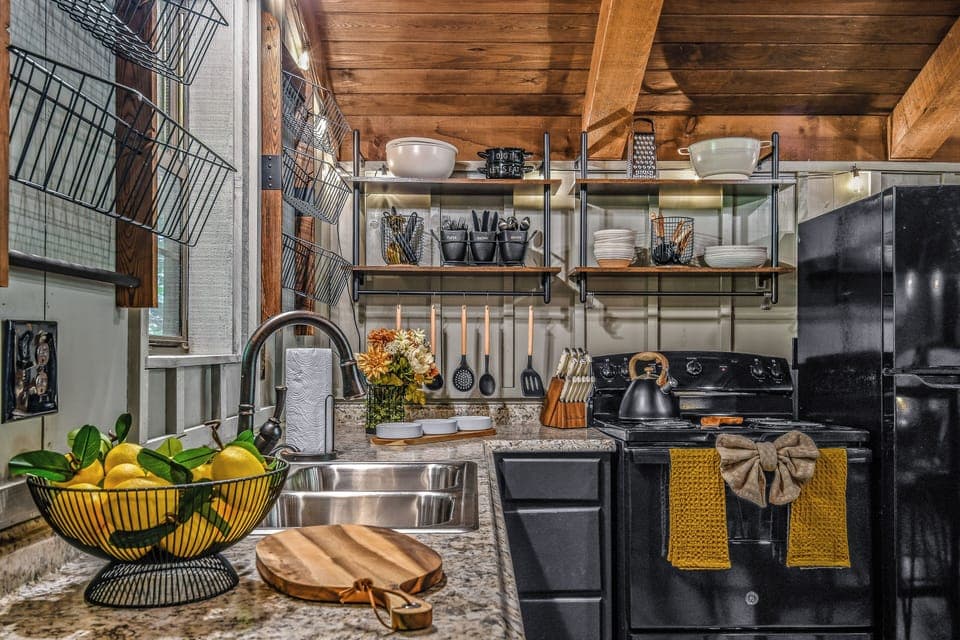 Fully equipped kitchen counter with stainless sink, open shelving, and all cooking essentials at Light'n Bug Bungalow studio cabin in Townsend, Tennessee