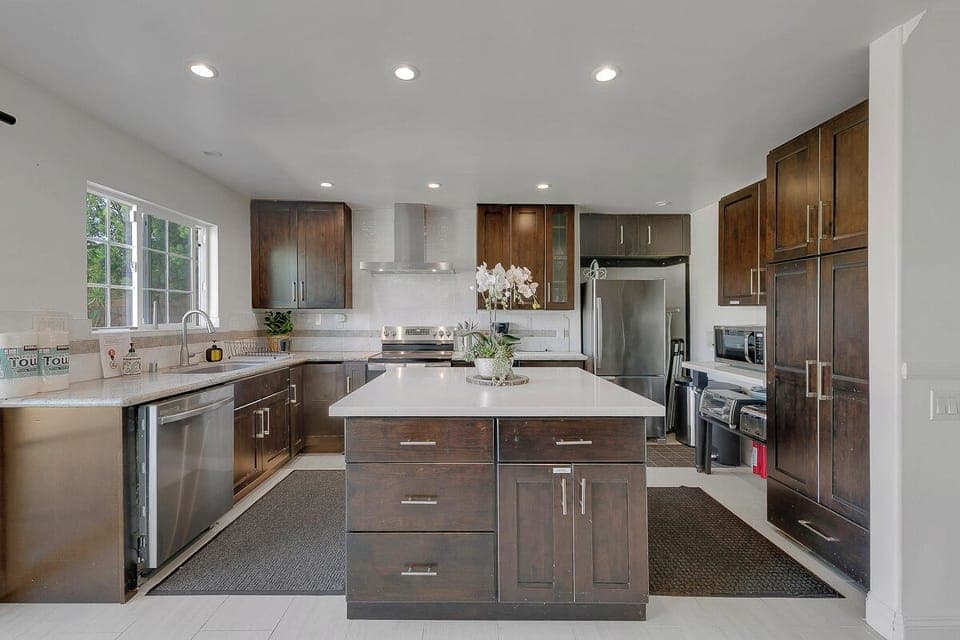 Large, bright kitchen with dishwasher, sink, refrigerator, electric stove, oven