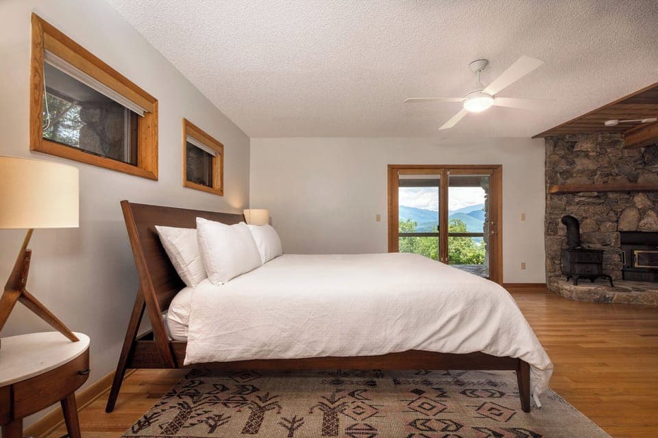 Lower-level primary suite with king-size bed, gas log fireplace, 55" Smart TV, en suite bathroom, and access to the lower level deck
