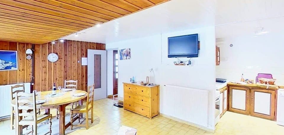 The spacious and inviting living area is perfect for gathering with loved ones. It features a large dining table with ample seating for everyone, ideal for enjoying meals together. The wooden walls and ceiling create a warm and cozy ambiance, reminiscent 