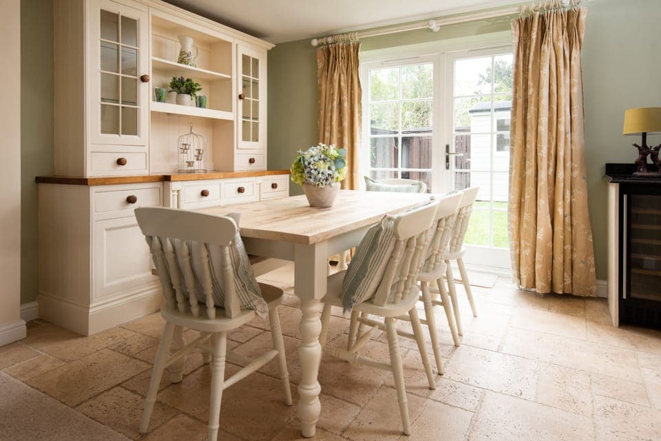 Light & airy dining area with farmhouse table & french doors opening onto back garden