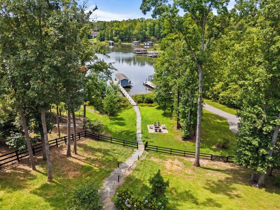 A picturesque lakefront property featuring a serene dock, lush greenery, and a cozy fire pit, perfect for relaxation and outdoor enjoyment.
