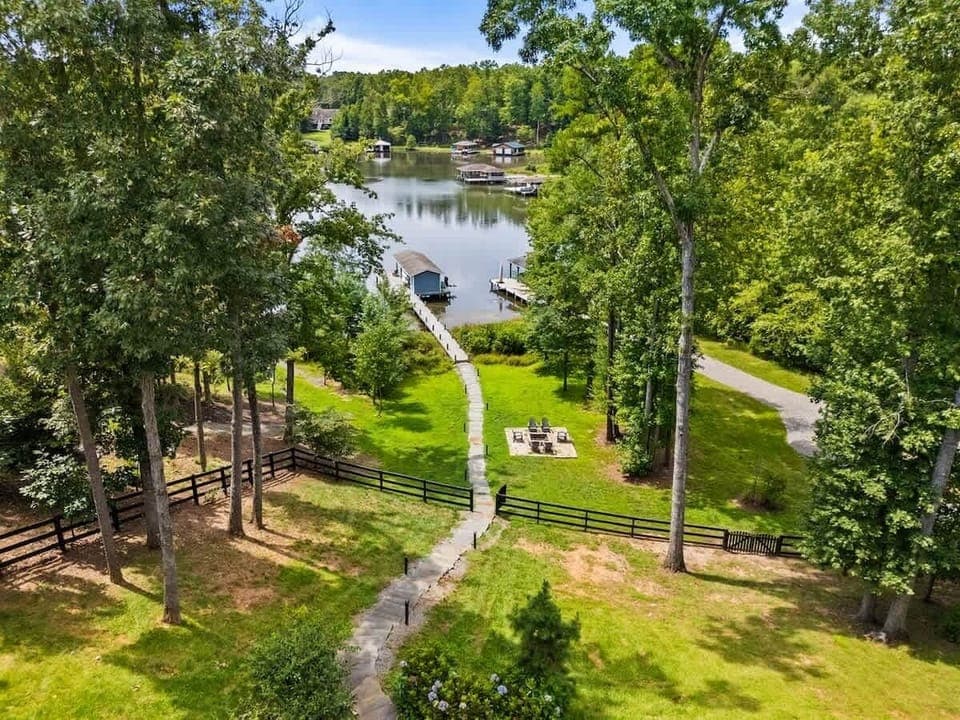 A picturesque lakefront property featuring a serene dock, lush greenery, and a cozy fire pit, perfect for relaxation and outdoor enjoyment.