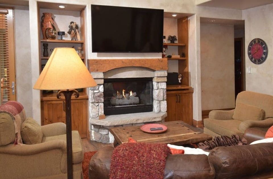 Relax in the cozy living room, featuring a warm fireplace, comfortable seating, and a large flat-screen TV for entertainment.