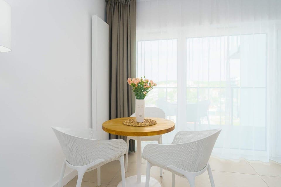 Another view of the round dining table by the window, showing the pleasant natural light and decoration.