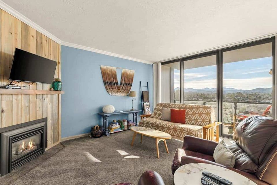 Inviting living room featuring a cozy fireplace, large windows, and stunning mountain views—ideal for unwinding.