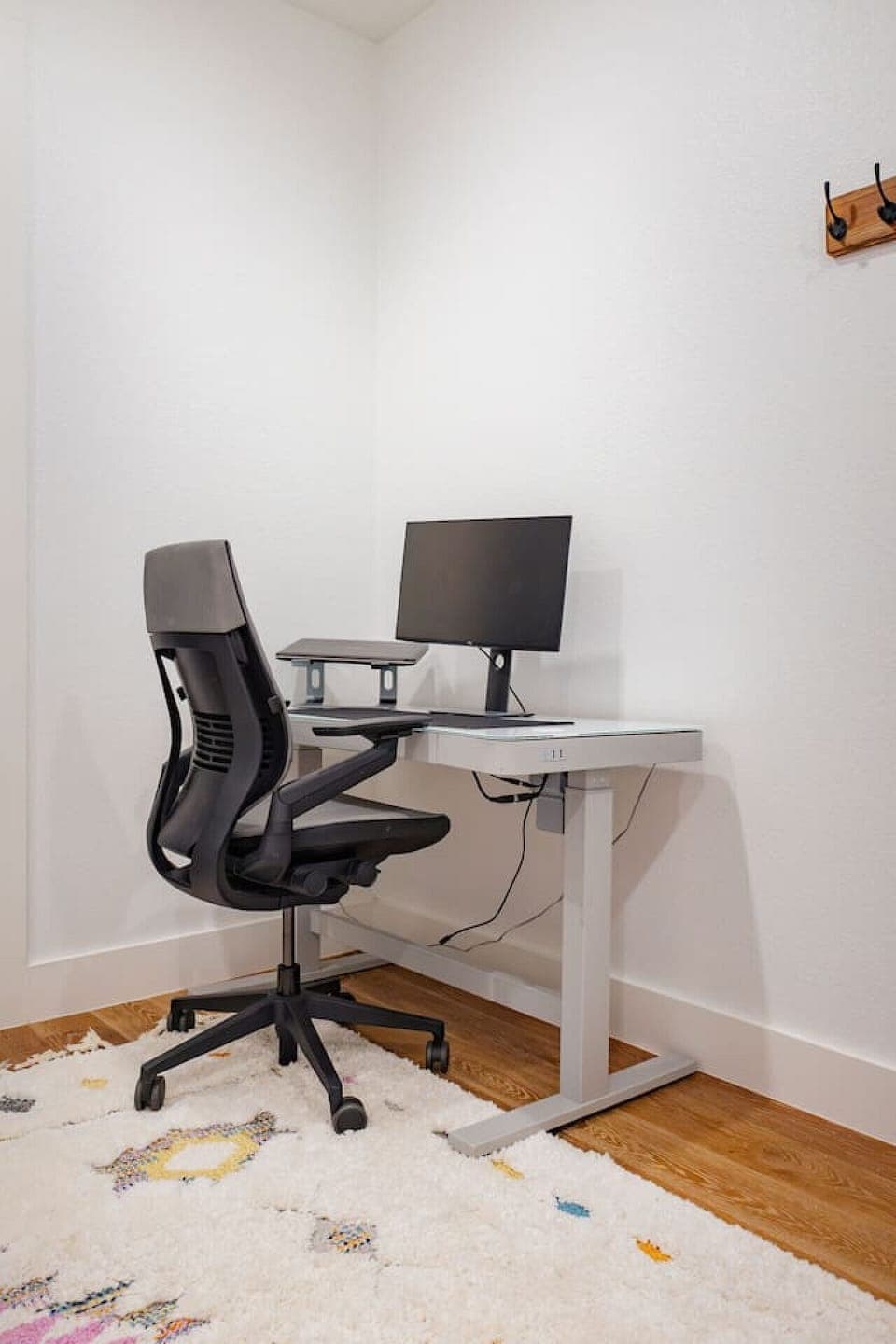 Work station in office with electric stand up desk, laptop riser and chair.