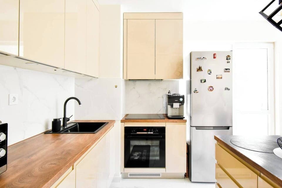 This modern kitchen blends functionality with sleek design, featuring high-quality appliances and ample counter space. The combination of light cabinetry and wood accents creates a warm, inviting atmosphere, making it a perfect spot for cooking and enjoying meals.