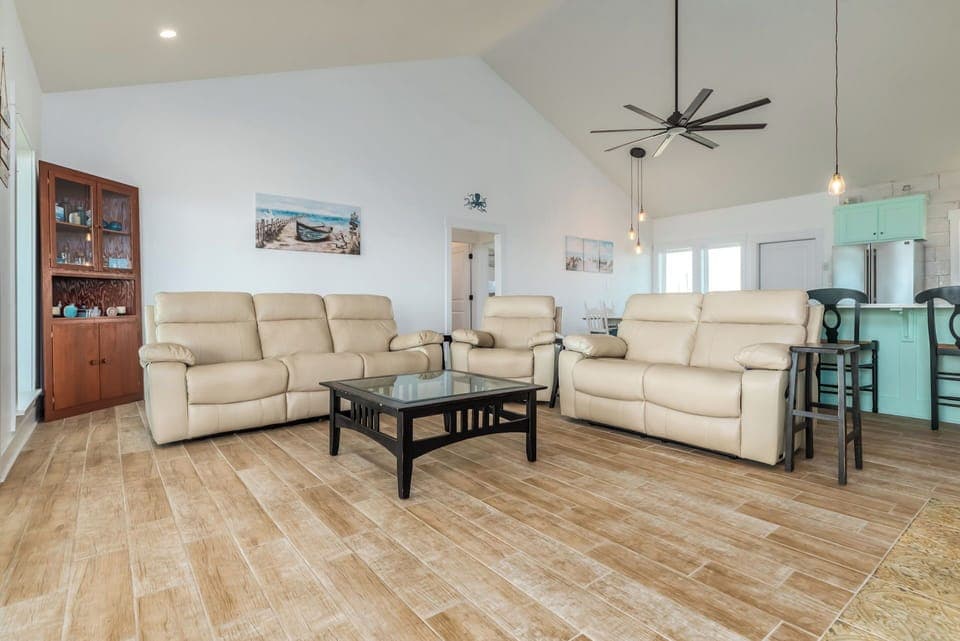 Sink into plush leather sofas in your open-concept living space, where coastal artwork and modern comfort create the perfect retreat.