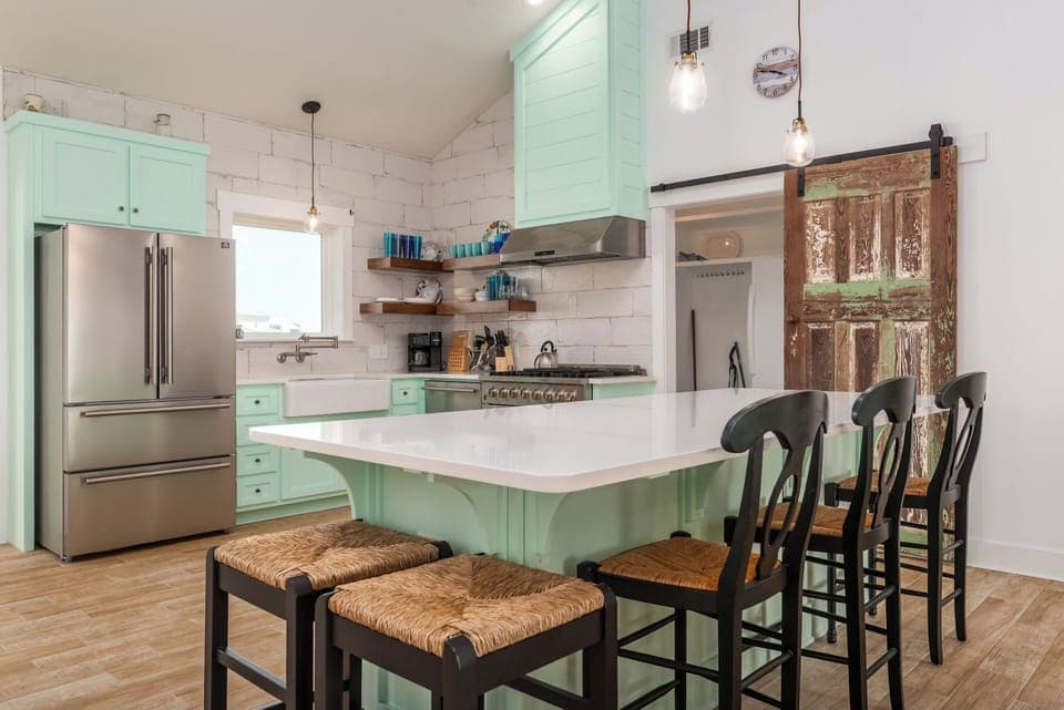 Whip up your favorite meals in this charming kitchen with mint green cabinets, marble counters, and rustic barn door details.