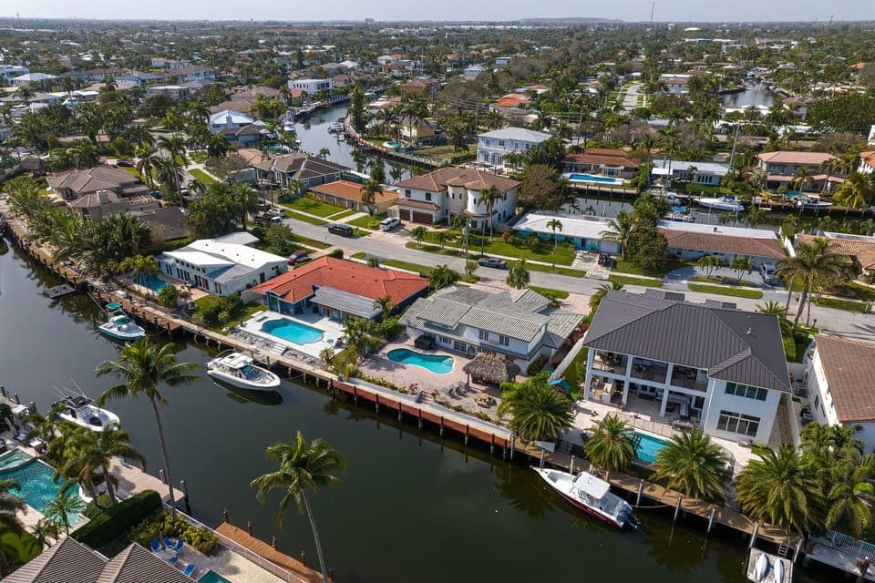 A stunning aerial view of a waterfront neighborhood with docks, pools, and peaceful canal views - the perfect coastal escape.