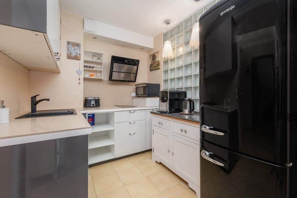  A modern kitchenette with sleek white cabinets and all the essentials, perfect for preparing meals in a compact yet functional space.