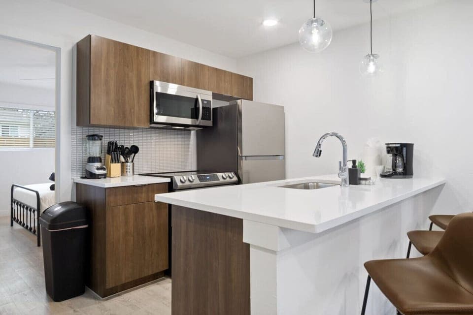 Prepare meals in this modern, fully-equipped kitchen featuring stainless steel appliances and a spacious island with bar seating. The open layout makes it easy to cook and entertain, ensuring a delightful culinary experience during your stay.