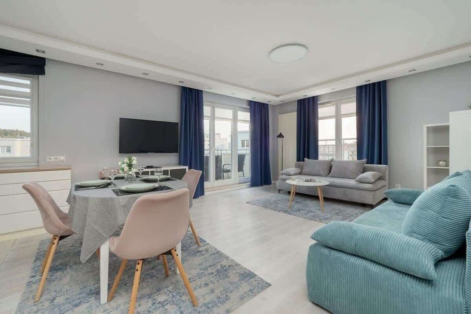 Modern living room with sofas, blue curtains, and a coffee table.