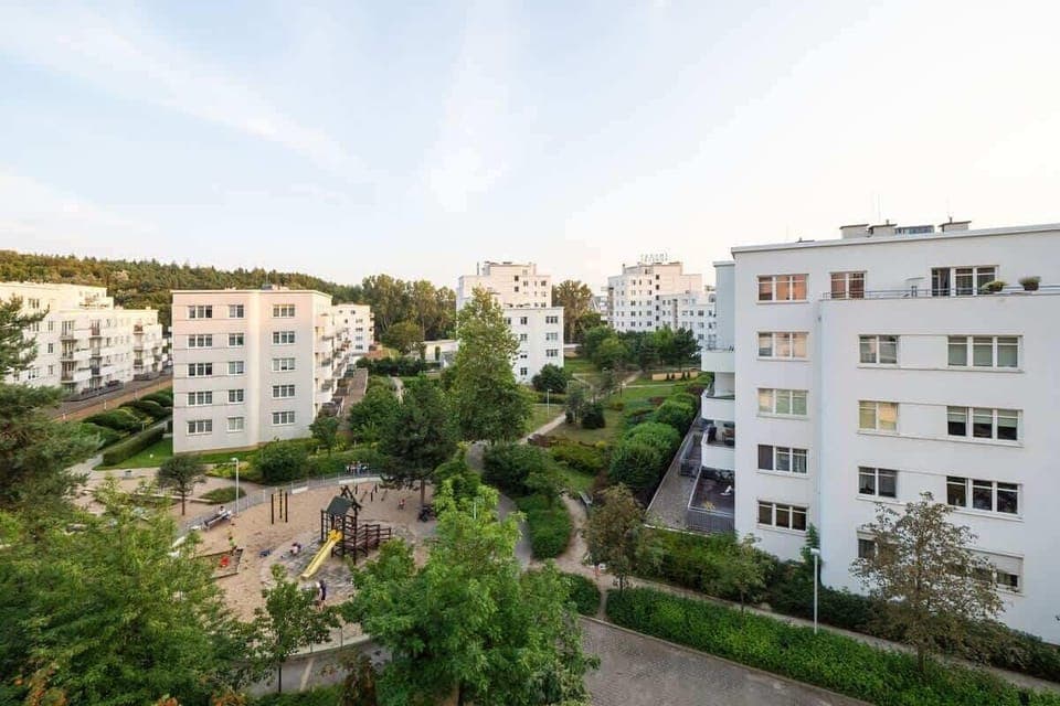 View from an apartment balcony showing residential buildings and greenery.