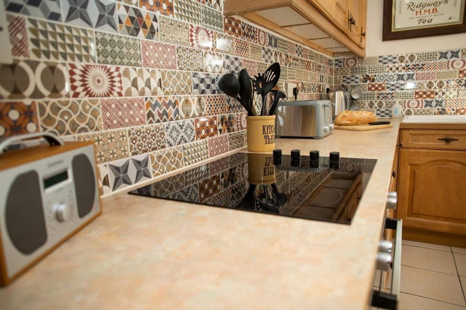 Kitchen with electric hob, toaster and patterned wall tiles
