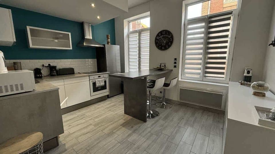 Cuisine équipée avec four, plaques de cuisson, bouilloire, machine à café, micro-ondes, grille-pain et réfrigérateur avec congélateur.
Coin repas pour quatre personnes.
La cuisine est ouverte sur le salon.