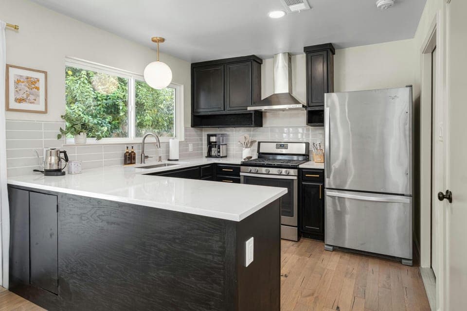 Enjoy our fully stocked kitchen with sleek black cabinets and pristine white quartz countertops that offer a modern, stylish space where you can easily prepare meals or grab a quick snack, with everything from pots and pans to handy appliances within reach. 