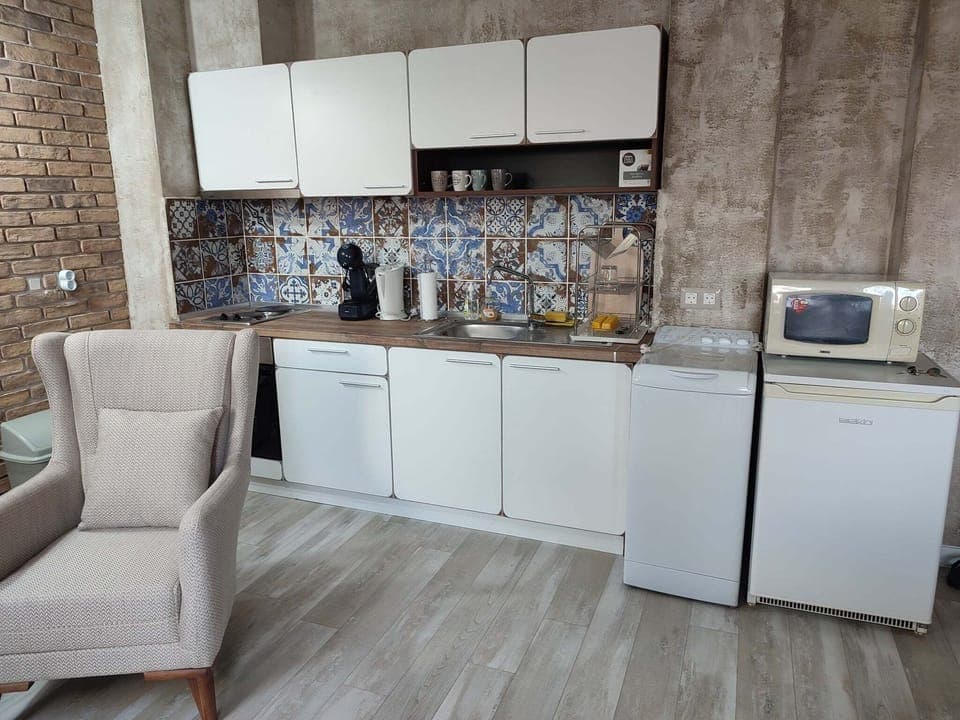 View of the kitchen corner. Microwave, washer and a fridge on the right side.