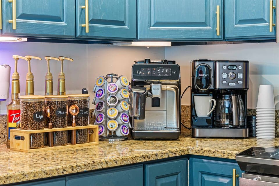 Indulge in a premium coffee experience with a fully stocked espresso bar—featuring a Philips automatic espresso machine, K-Cup, pot, french press, and a curated selection of beans, sugars, and syrups.