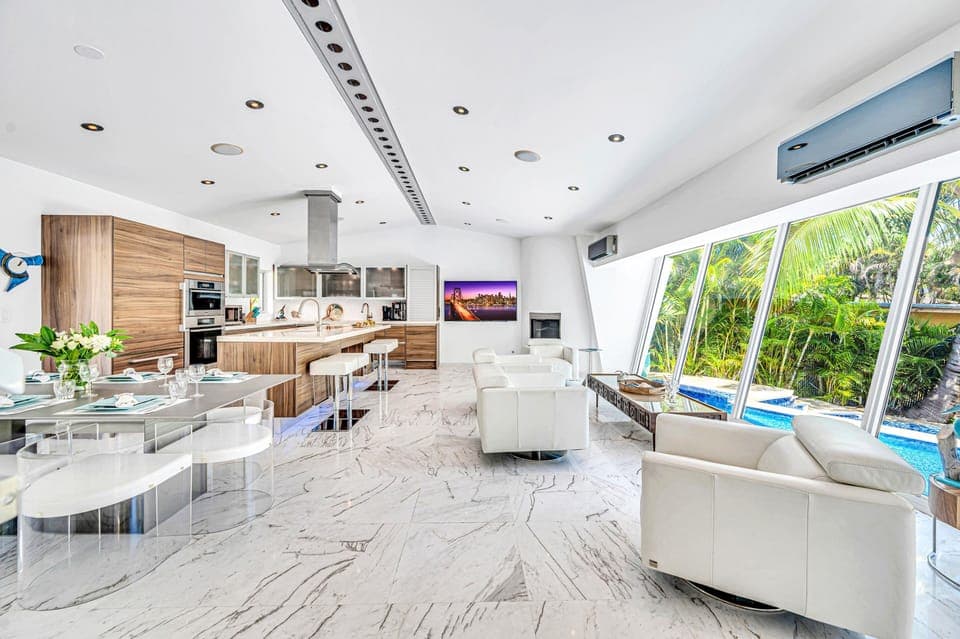 The open-concept living, dining, and chef's kitchen are bathed overlooking the tranquil canal and heated pool.