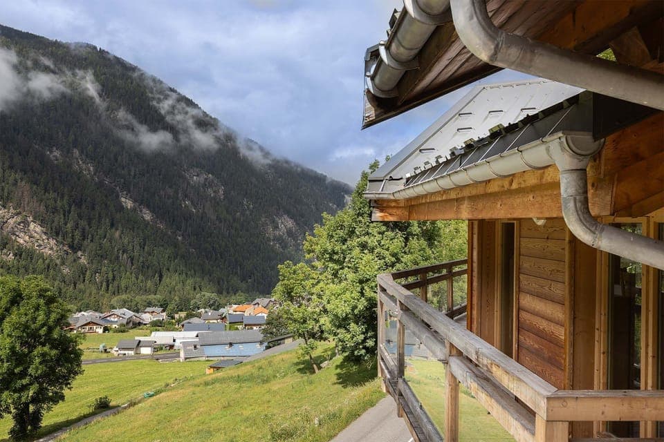 Enjoy serene views of the valley and mountains from this wooden balcony, offering a peaceful space to relax and take in the natural beauty surrounding the property.