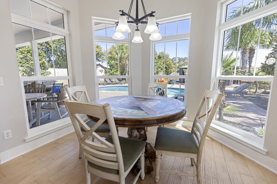Gather around this charming dining table where your morning coffee tastes better with poolside views through floor-to-ceiling windows.