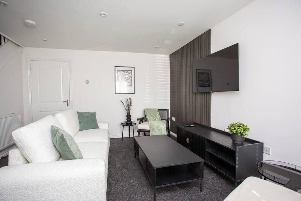 This living room features a bright and airy atmosphere, with its crisp white walls and matching white sofas that create a clean and elegant look as you sit right in front of the TV