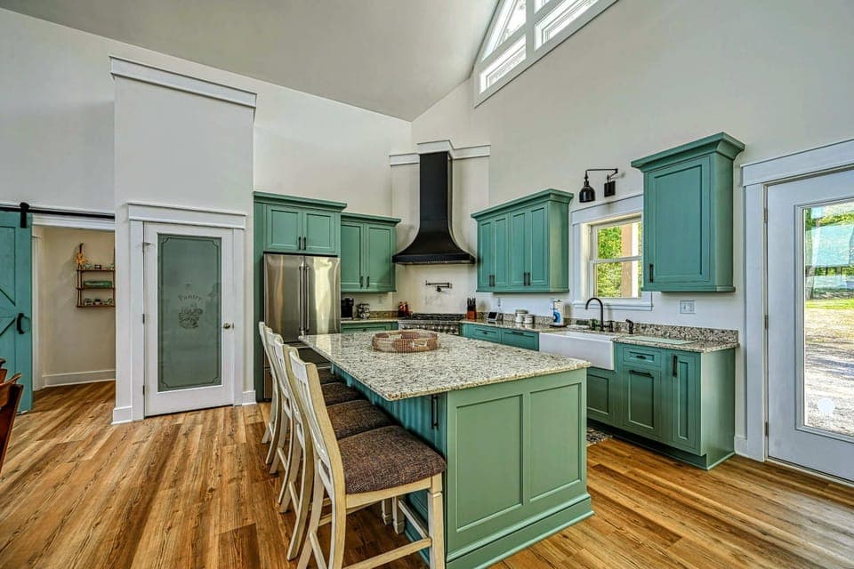 Spacious and modern kitchen with a large island, stylish green cabinetry, and plenty of natural light, perfect for cooking and entertaining