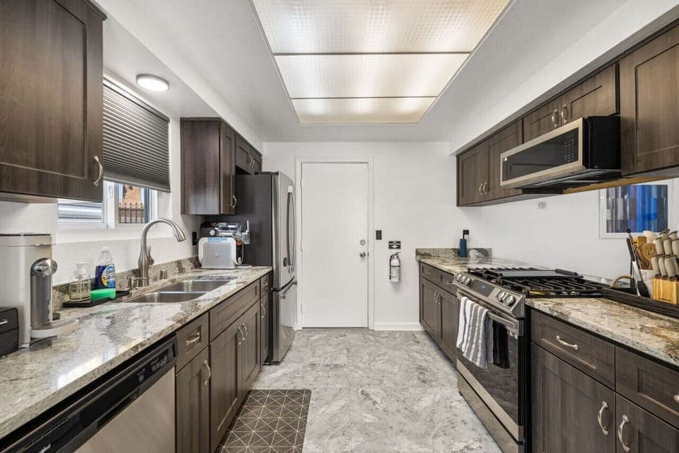 Sleek galley kitchen w/ stone counters, modern appliances, and streamlined layout for easy cooking.