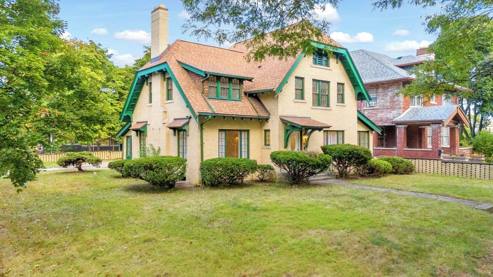 Inviting two-story yellow brick home with green trim