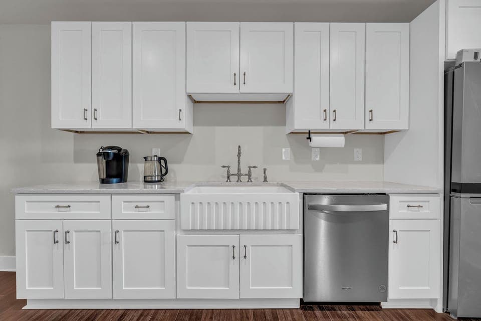 Bright, minimalist kitchen featuring sleek white cabinets &  modern appliances