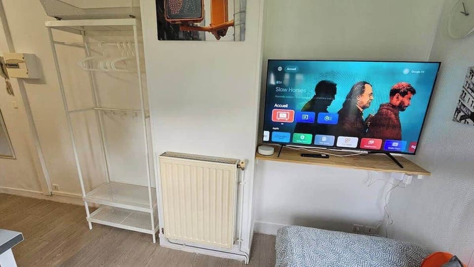 Espace chambre avec un lit simple et télévision.
L'espace de vie est ouvert sur la kitchenette.