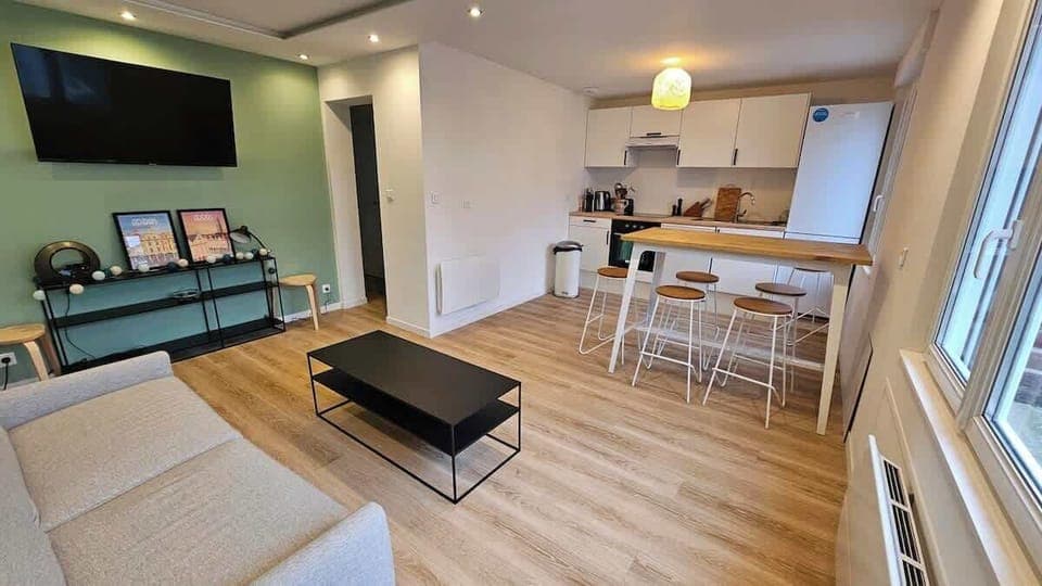 Salon avec canapé convertible et télévision.
Le salon est ouvert sur la cuisine avec l'espace repas.