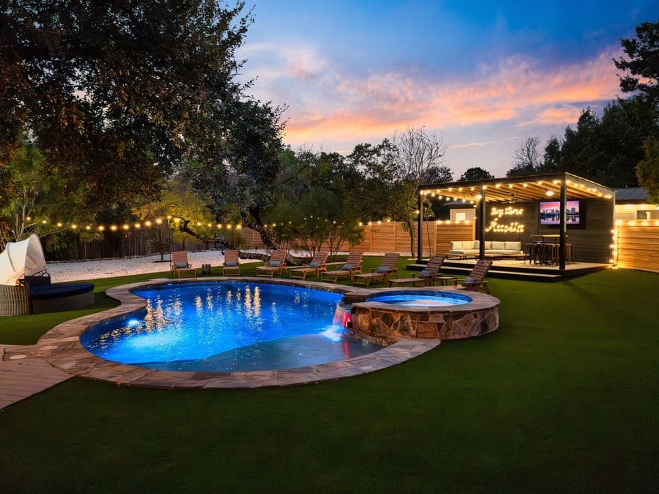 This backyard oasis with a glowing pool and hot tub is pure city magic at night.