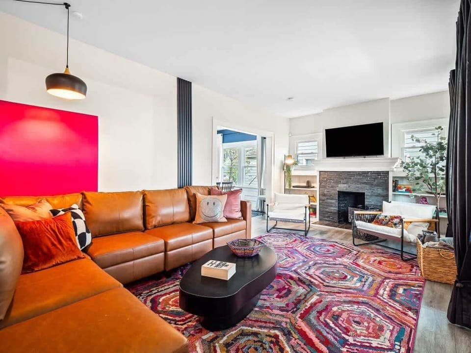 - Bright living room with modern leather sofa and bold colorful rug   - Fireplace with TV for cozy evenings and stylish gatherings   - Relax with vibrant design and spacious seating area  