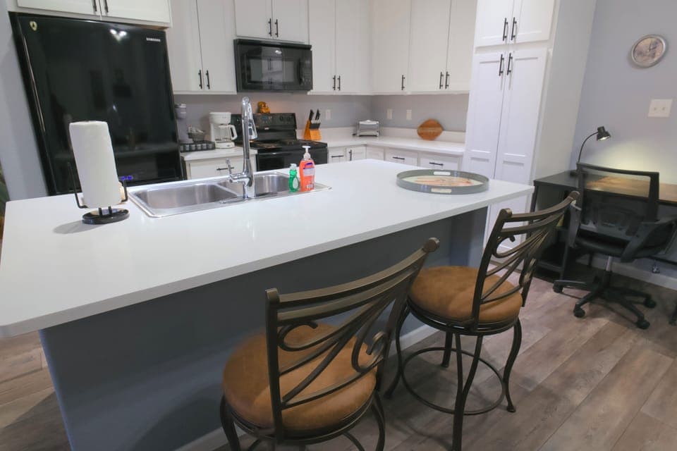 Dedicated workspace with desk, chair, and lamp between kitchen and dining area.