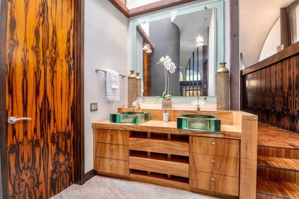 An exquisite blend of elegance and artistry – the delicate beauty of an orchid, artistic dual sinks and luxurious wood finishes. Light-painted walls and a large mirror reflect a space that’s as stunning as it is functional.