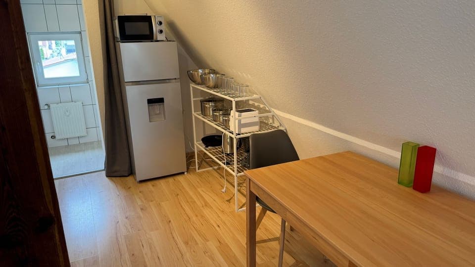 Esstisch, Kühlschrank, Mikrowelle und Zubehör.