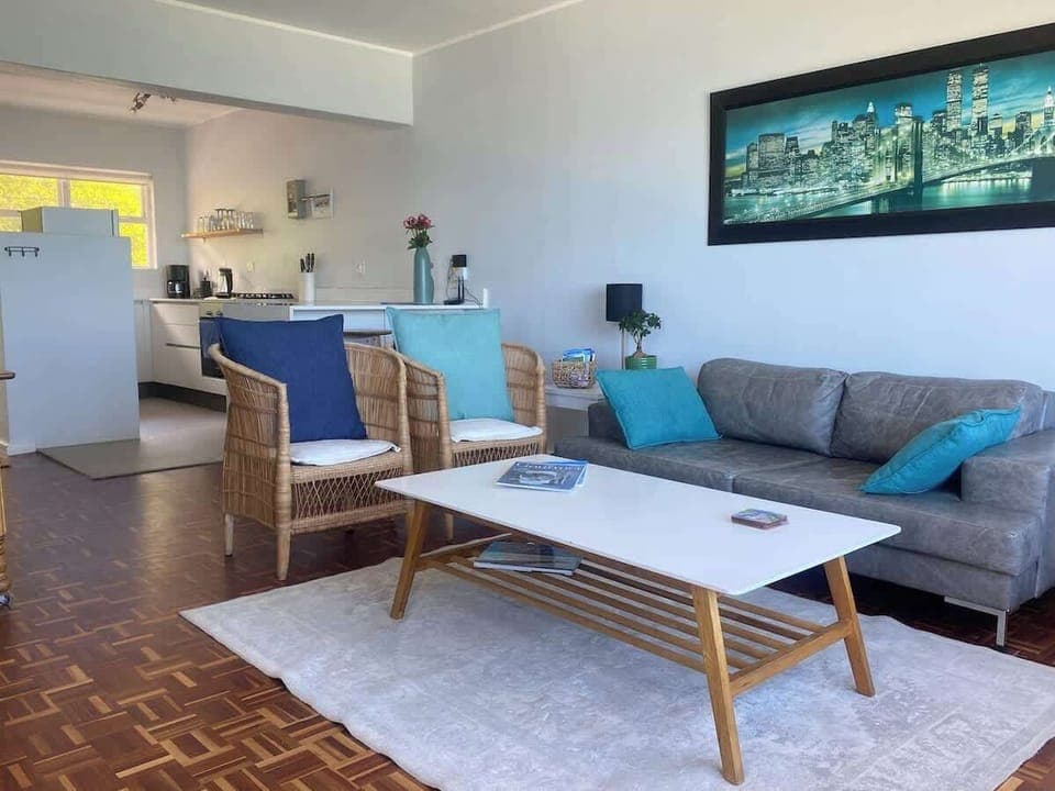 A comfortable lounge with open plan living into the kitchen with a dining area to the left. Perfect for watching TV or watching the boats come in and out of the harbour. See further on for the lounge view!