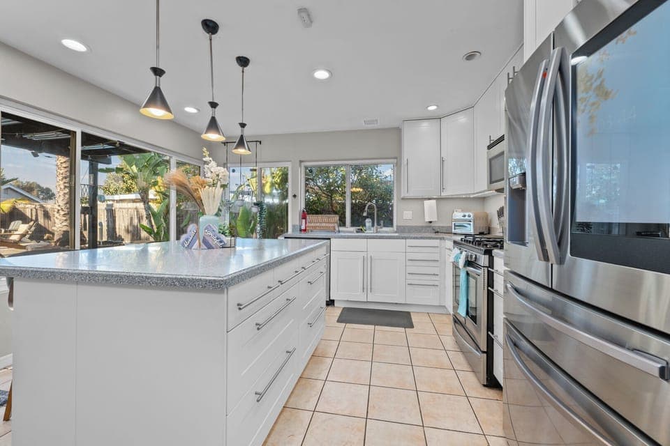 Modern kitchen with white cabinets, island, and stainless appliances.