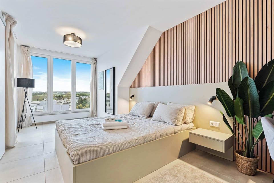 Inviting Living and Sleeping Space – Unwind in a cozy area featuring a queen-sized bed and a sophisticated wooden accent wall.