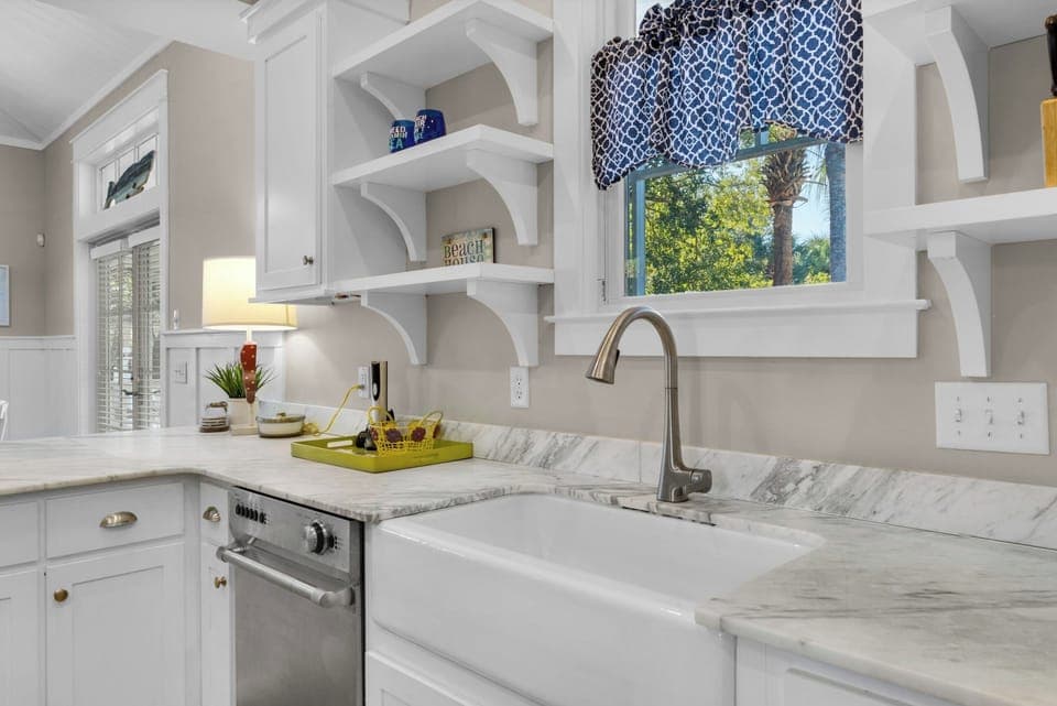 Your chef-inspired kitchen features marble countertops, farmhouse sink, and charming coastal details for memorable meal preparation.