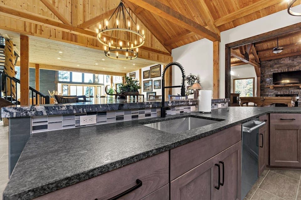 Granite counters span the width of the kitchen, beautifully accented by tile backsplashes and rows of hardwood cabinetry above and below, combining practicality with sophisticated design.